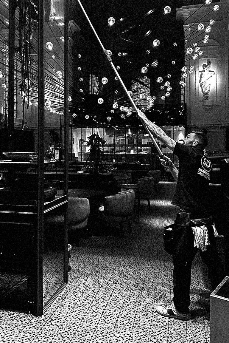 Medewerker van SD Window Cleaning aan het werk in een restaurant